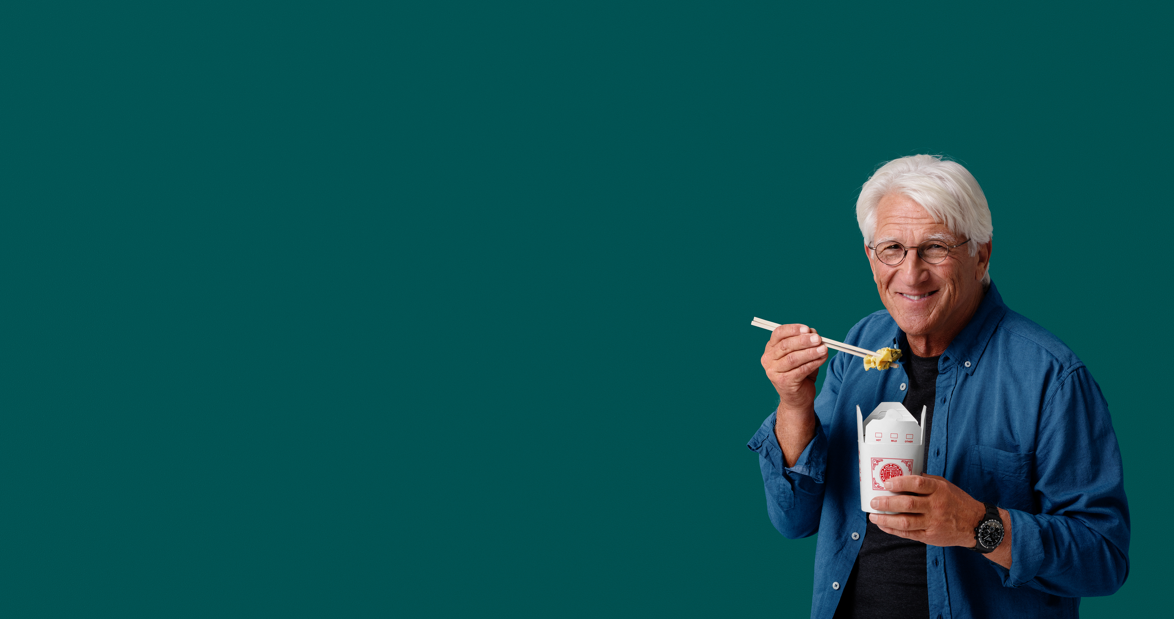 Aktiv pensionär Man äter ur snabbmatsförpackningen med ätpinnar